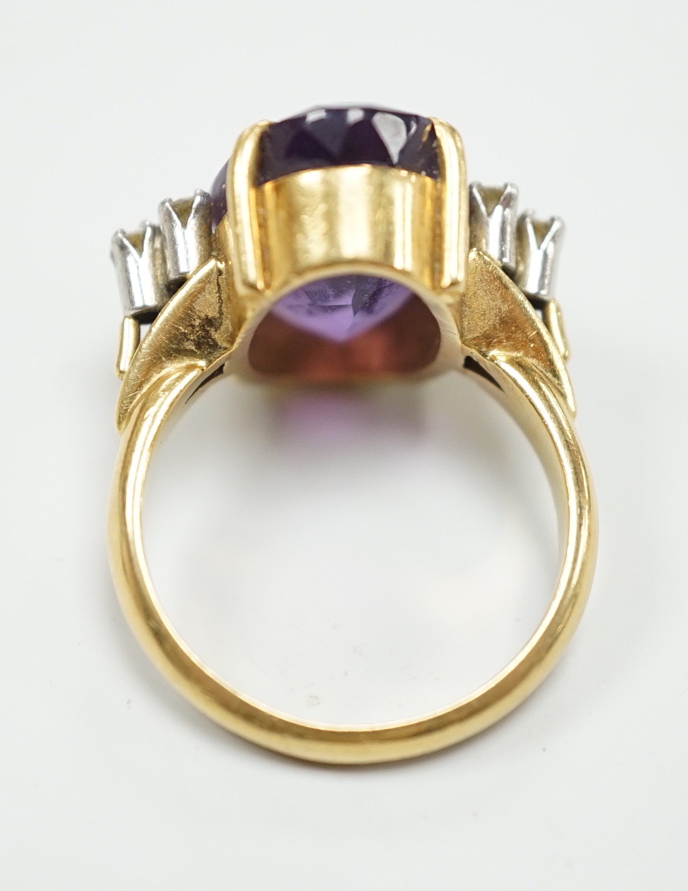 A yellow metal and oval cut amethyst set dress ring, with six stone diamond set shoulders, size O, gross weight 9.6 grams.